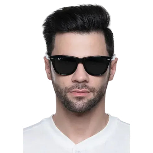 A man with styled dark hair and a short beard wearing black Ray-Ban sunglasses with white temple tips, against a light gray background.